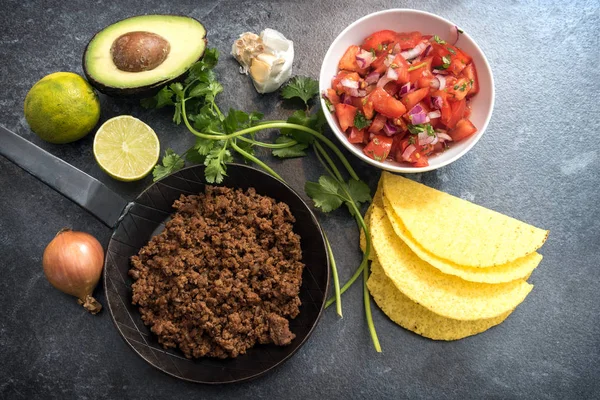 Ingredientes para tacos mexicanos con tomates asados y aguacate sobre un fondo de piedra oscura, vista superior desde arriba — Foto de Stock