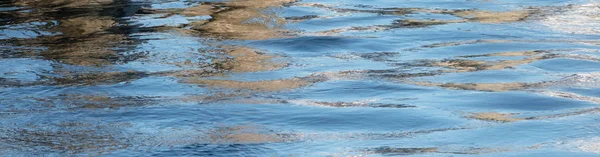 Blue water surface with small ripples or waves and dark reflections as a panoramic banner background with copy space — Stock Photo, Image
