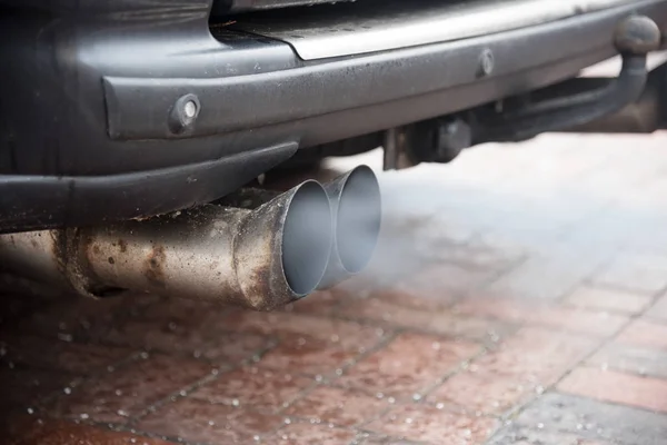 Dubbele uitlaat van een oudere auto met dieselmotor blaast gas met hoge fijnstof vervuiling, kopie ruimte — Stockfoto