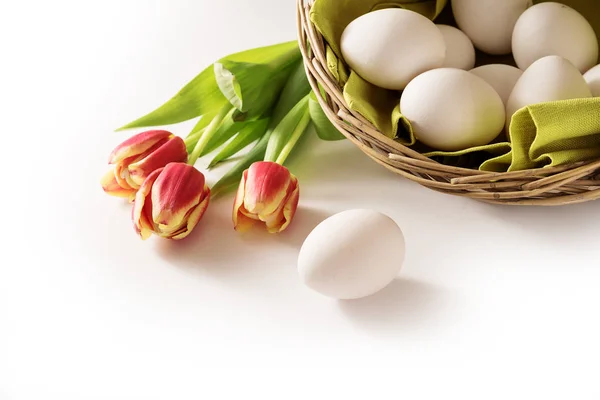 Ovos de Páscoa frescos em uma cesta e tulipas vermelhas como um fundo de canto de férias que desaparece para branco, espaço de cópia — Fotografia de Stock