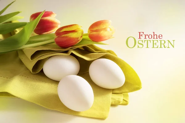 Huevos blancos en una servilleta verde y tulipanes rojos, texto alemán Frohe Ostern que significa Feliz Pascua, tarjeta de felicitación de vacaciones — Foto de Stock