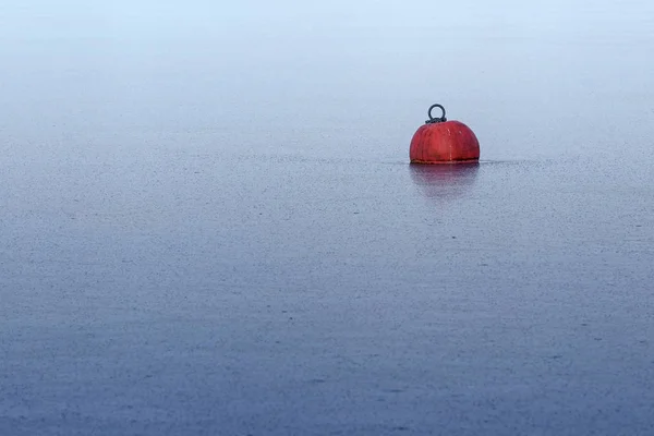 Rode boei in bevroren ijs op het blauwe water in een meer of zee, abstracte achtergrond voor winterseizoen en yachting pauze, metafoor van impasse, royale kopie ruimte — Stockfoto