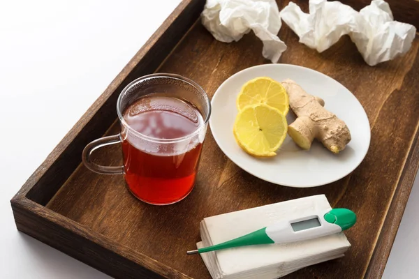 Деревянная таблетка для больного с простудой или гриппом, включая горячий чай, медицинский термометр, витамины и бумажные салфетки, медицинская концепция лечения на дому — стоковое фото