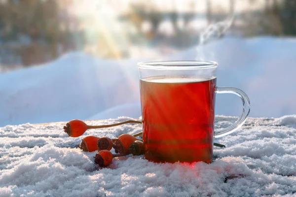 Hot red tea from hibiscus and rose hip fruits outdoors in the snow with sunbeams, healthy warming drink for immunity protection against cold and flu, copy space — Stock Photo, Image