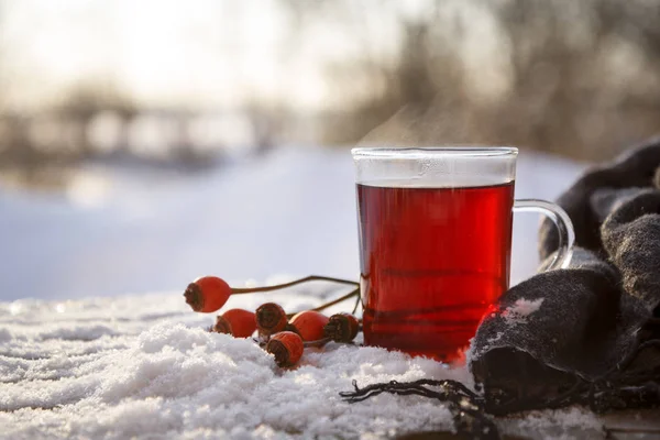 Hot tea from rose hips and hibiscus with fruits and a scarf outdoors on a cold winter day, the medical home remedy against flu contains vitamins and protects the immune system, copy space — Stock Photo, Image