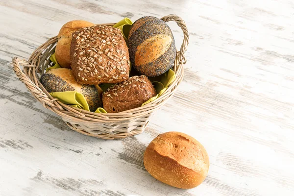 各種ロールやライ麦全粒小麦からパンをパンし、ケシの実バスケットと素朴な白い木製のテーブル、コピー スペース — ストック写真