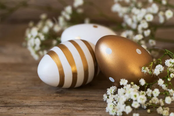 Ovos de Páscoa pintados com padrões de cobre dourado e flores de gypsophila em madeira rústica — Fotografia de Stock