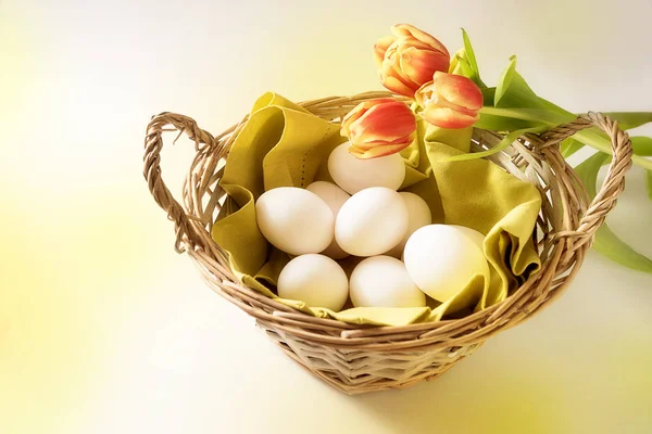 Cesta con huevos de Pascua blancos y tulipanes rojos, concepto de vacaciones con espacio para copiar — Foto de Stock