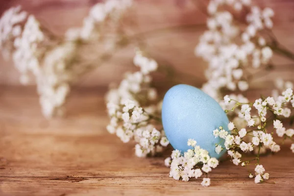 Ovo de Páscoa azul e gypsophila (flor de respiração de bebê) em um fundo de madeira rústica com espaço de cópia — Fotografia de Stock