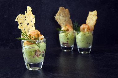 Avokado krem veya guacamole karides ve peynirli gevrek bir karanlık arduvaz arka plan kopya alanı ile üzerinde cam, meze veya parti snack