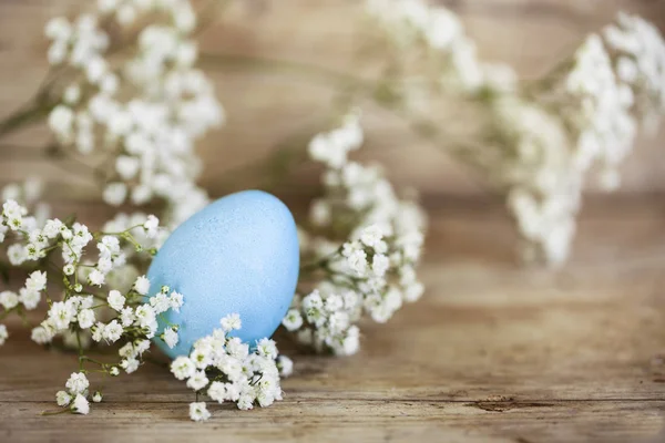 Uovo di Pasqua blu e gypsophila (fiore respiro bambino) su uno sfondo di legno rustico con spazio copia — Foto Stock