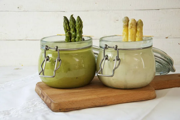 Спаржа кремовый суп белый и зеленый креативно подается в стеклянных банках на деревянной доске, яркий фон — стоковое фото