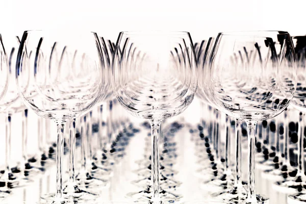 many wine glasses in rows for a festive dinner against a light background