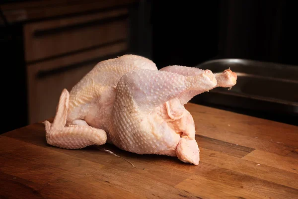 Seluruh organik mentah ayam pada blok tukang daging kayu gelap — Stok Foto