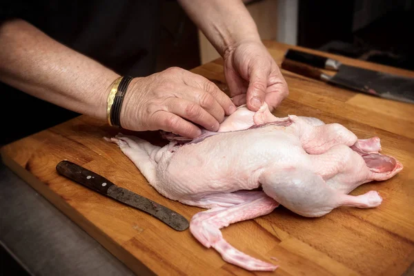 Mãos masculinas preparar um pato cru para cozinhar em um bloco de talho de madeira rústica — Fotografia de Stock