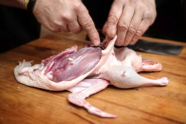 Tangan laki-laki mempersiapkan bebek mentah untuk mendapatkan fillet payudara untuk memasak pada balok daging kayu pedesaan — Stok Foto