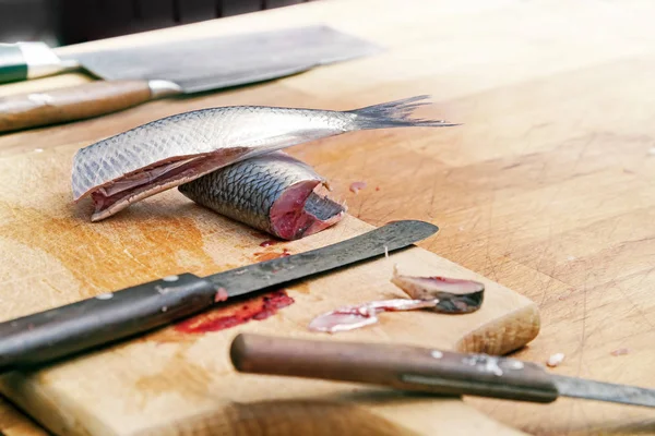 Preparing herring, fish slices and various knives on a rustic wooden cutting board, copy space — Stock Photo, Image