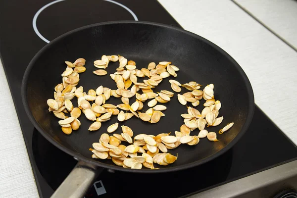 Гарбузове насіння смажать на чорній сковороді, тема приготування — стокове фото