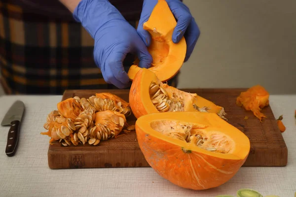 Voorbereiding van pompoen, verwijder vrouw handen met blauwe rubberen handschoenen de zaden uit het fruit — Stockfoto