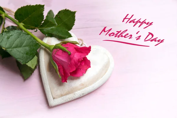 Rose sur une forme de coeur en bois sur un fond rose vif, texte Bonne fête des mères, vue du dessus avec espace de copie — Photo