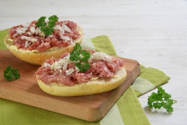 Ekmek rulo ile kıyılmış domuz sosisi, soğan ve maydanoz ile Alman zwiebelmettwurst bir kahvaltı masa, yeşil peçete ve Beyaz ahşap arka plan üzerinde kopya alanı ile garnitür