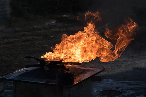 Brand op een ijzeren pan, blussen demonstratie tijdens een training van de brandweer, donkere achtergrond met kopie ruimte — Stockfoto