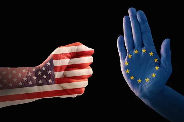 Conflito comercial, punho com bandeira dos EUA contra uma mão com bandeira europeia, isolado em um fundo preto — Fotografia de Stock