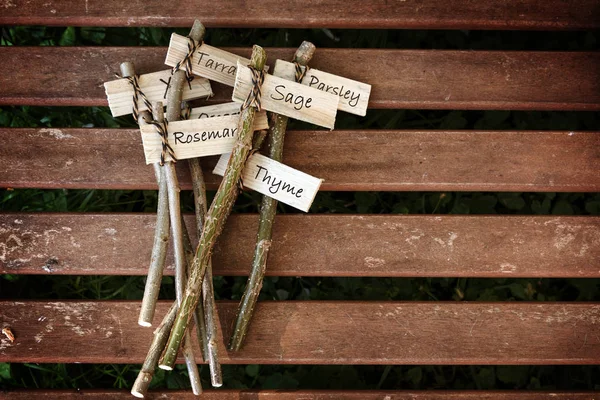 Marcadores de plantas criativas em uma mesa de madeira rotulada com nomes de ervas para o jardim rural, faça você mesmo conceito — Fotografia de Stock