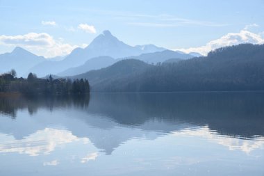 weissensee, idyllic lake in dusty morning light front of the blue mountains of the bavarian alps near fuessen in the allgaeu, germany, copy space clipart