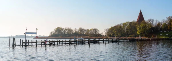 Lång träbrygga i yacht hamnen vid kyrkan i en vik på ön Poel nära Wismar i Östersjön, Tyskland, blå himmel med kopieringsutrymme, panorama format — Stockfoto