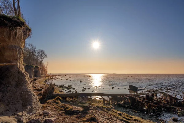 Kvällssol med strålar reflekteras i vattnet vid den branta kustklippan på den tyska ön Poel i Östersjön nära Wismar, kopiera utrymme på himlen — Stockfoto