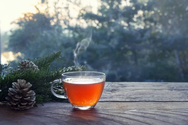 Beker met hete stomende thee op een rustieke houten tuintafel met kerstversiering op een winterdag, gezondheidsconcept tegen kou en griep, kopieerruimte — Stockfoto
