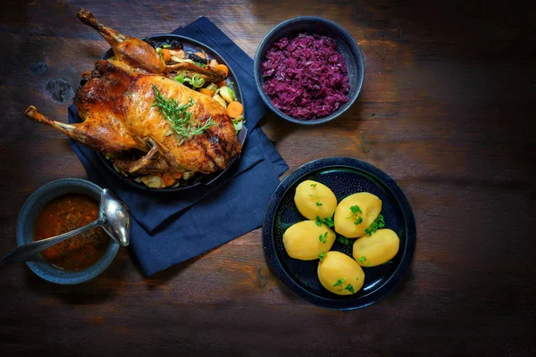 Bebek panggang dengan kentang, kubis merah dan saus, makanan meriah di atas meja kayu pedesaan yang gelap, ruang fotokopi, sudut pandang yang tinggi dari atas — Stok Foto