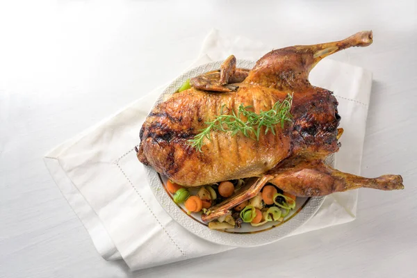 Seluruh bebek panggang dengan sayuran, makan malam Natal yang meriah disajikan di atas serbet dan meja putih, ruang fotokopi, sudut pandang yang tinggi dari atas — Stok Foto