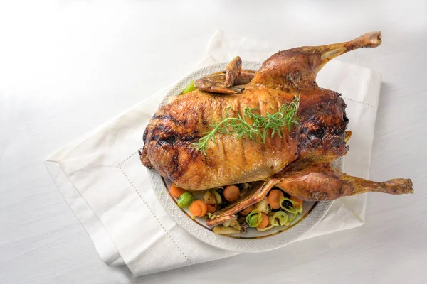 Anatra intera arrosto con verdure, cena di Natale festiva servita su un tovagliolo e un tavolo bianco, spazio copia, vista ad angolo alto dall'alto — Foto Stock