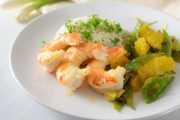 Ied plato de camarones de gambas tigre con guisantes de azúcar, cebolla y naranjas servidas con arroz y perejil adornar en un plato blanco — Foto de Stock