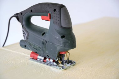 electric jigsaw saws up a wooden board, tool for professional or hobby handicraft, copy space