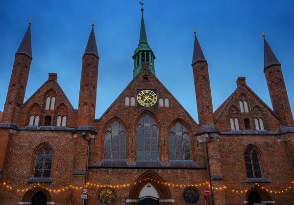 Gebouw en torens van het Heiligen Geist Ziekenhuis in het oude centrum van Luebeck, een historisch bakstenen gebouw uit de middeleeuwen bij zonsondergang tegen de donkerblauwe hemel — Stockfoto