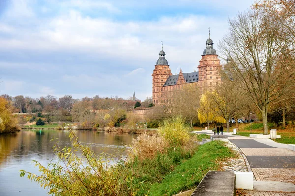 Schloss johannisburg am Main mit herbstlicher Uferpromenade in Aschaffenburg, berühmtes historisches Stadtschloss aus rotem Sandstein, wolkenblauer Himmel mit Kopierraum — Stockfoto