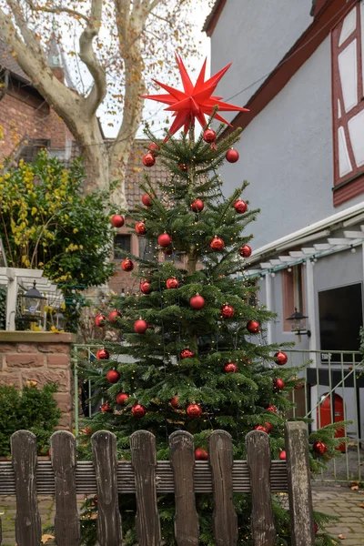 Weihnachtsbaum geschmückt mit roten Kugeln und Lichterkette im Freien in einer Altstadtgasse in Aschaffenburg, Bayern, Deutschland — Stockfoto