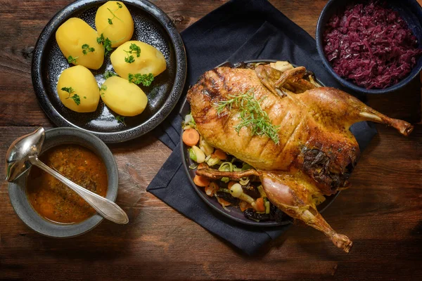 Bebek panggang dengan kentang, kubis merah dan saus, makanan meriah di atas meja kayu pedesaan yang gelap, pemandangan sudut yang tinggi dari atas — Stok Foto