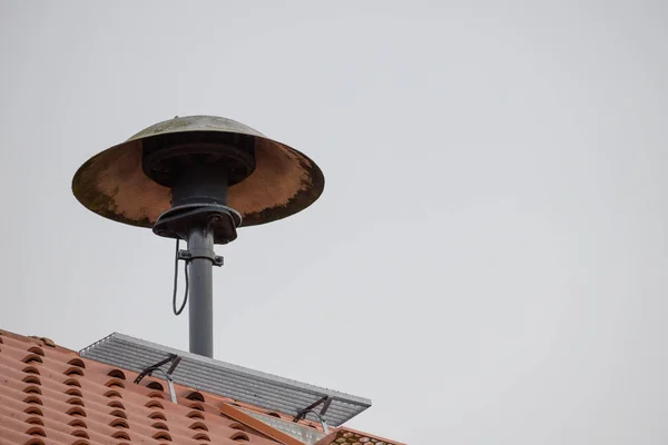 Fire siren on a roof to alarm the fire fighter brigade in case of an emergency, gray sky with copy space — Stock Photo, Image