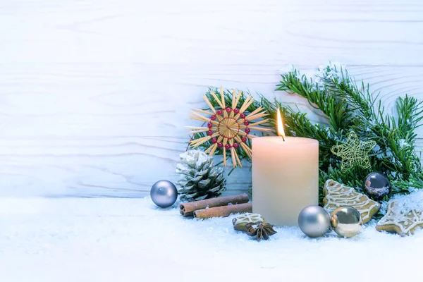 Brennende Kerze und Weihnachtsdekoration auf Schnee vor weißem Holzgrund, Kopierraum — Stockfoto