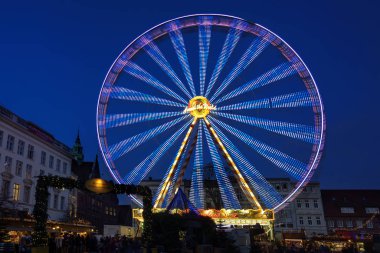 Luebeck, Almanya, 18 Aralık 2019: Eski Luebeck kasabasındaki Noel pazarında gece dönen dönme dolap, uzun süre mavi saate maruz kalma