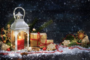 Mum ışığı feneri ve kardaki Noel süsü ile fotokopi alanı olan koyu mavi ahşap arka plan.