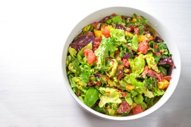 Taze salata, portakal, greyfurt, salam ve çam fıstığı büyük bir kâse içinde fotokopi alanı olan beyaz bir masada, yukarıdan yüksek açılı üst görüş.