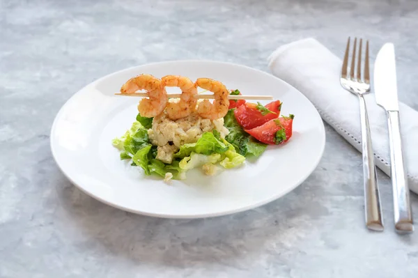 Festlig aptitretare från räkor spett på en blomkål risotto hög, sallad och tomater på en vit platta, ljusgrå bakgrund med kopia utrymme — Stockfoto