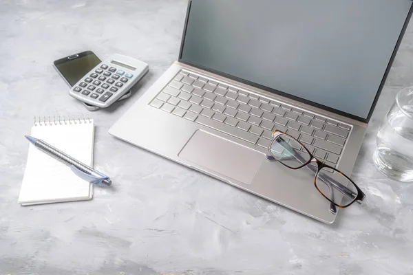 Local de trabalho com laptop, calculadora e óculos em uma mesa de escritório cinza com espaço de cópia — Fotografia de Stock