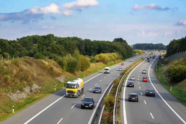 Autos und Lastwagen fahren auf der Autobahn durch Landschaft, Verkehrs- und Umweltkonzept, blauer Himmel mit Wolken und Kopierraum — Stockfoto