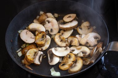 Siyah cam seramik bir tencerede kızartılmış mantar, sağlıklı vejetaryen yemek konsepti.